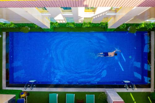 a person swimming in a large swimming pool at Fivitel Boutique Da Nang in Da Nang