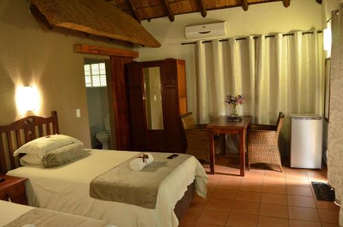 1 dormitorio con 2 camas, mesa y escritorio en Acasia Guest Lodge, en Komatipoort