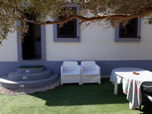 un patio con due sedie e un tavolo e un edificio di Casuzza cala pisana a Lampedusa