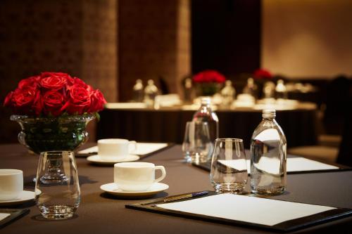 a table with a vase of red roses and glasses at L'Escape Hotel in Seoul