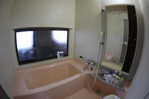 a bathroom with a bath tub and a window at Guesthouse Omihachiman in Omihachiman