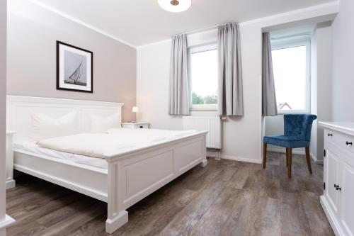 ビンツにあるstrandnahe FeWo mit 2 Schlafzimmern, Residenz Bel Vital - Kategorie Dの白いベッドルーム(大きな白いベッド1台、青い椅子付)