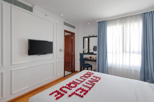 a hotel room with a bed and a flat screen tv at Fivitel Boutique Da Nang in Da Nang