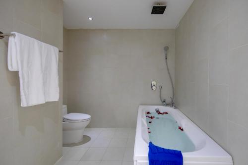 a white bathroom with a bath tub in it at Fivitel Boutique Da Nang in Da Nang