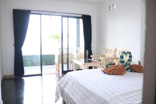 a bedroom with a bed and a large sliding glass door at Alur Beach Homestay in Amed