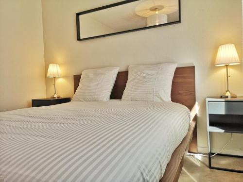 - une chambre avec un lit avec des draps blancs et 2 lampes dans l'établissement Chez Charlie - Centre ville Colmar - 2 pièces, à Colmar