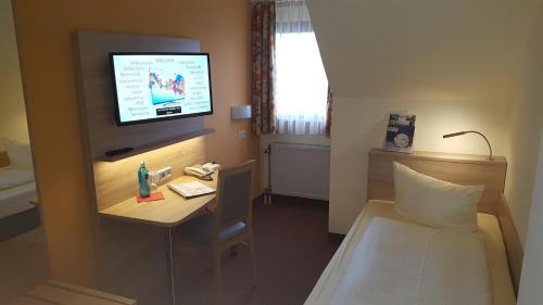 a room with a bed and a tv on a wall at Hotel Merian Rothenburg in Rothenburg ob der Tauber