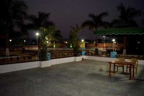 a table and chairs on a patio at night at Anand Agro Tourism Kashid in Alibaug