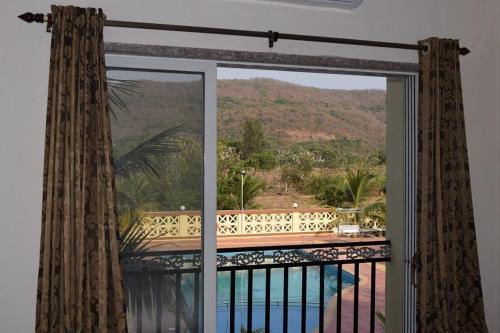 a room with a window with a view of a pool at Anand Agro Tourism Kashid in Alibaug
