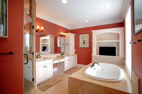La salle de bains est pourvue de murs rouges, d'un lavabo et d'une douche. dans l'établissement Beautiful 3Bed Townhome in Historic Downtown Savannah, à Savannah