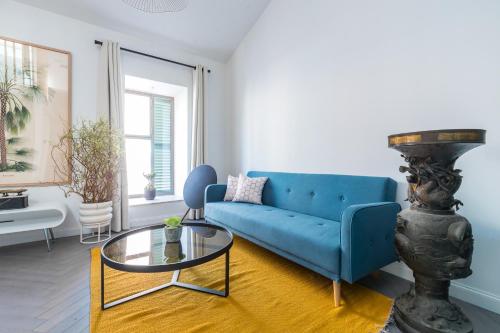 a living room with a blue couch and a glass table at L'Abeille - Boutique Apartments in Nice