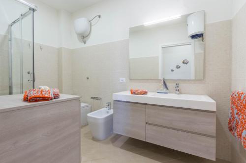 a bathroom with a sink and a toilet and a mirror at Blue Apartment IUN S0079 in Cala Gonone