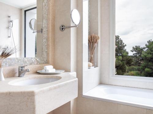 拉里薩的住宿－Grecotel Larissa Imperial，一间带水槽和浴缸的浴室以及窗户。