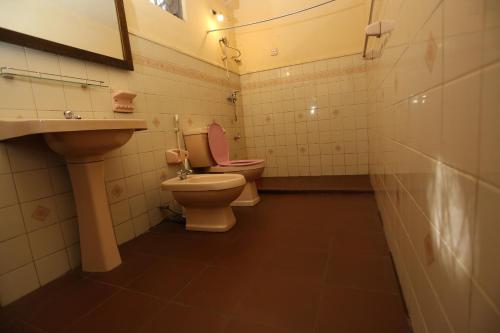 a bathroom with two toilets and a sink at Tree Breeze Inn in Kandy