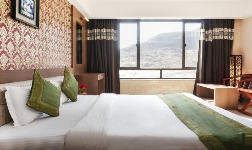 a bedroom with a large bed with a large window at Shri Vitthal Mangalam Satara in Satara