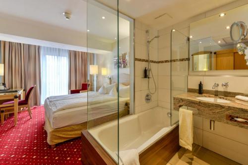 ein Bad mit einem Bett und einer Badewanne neben einem Schlafzimmer in der Unterkunft Hotel Pöker in Meppen