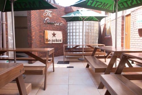 a restaurant with wooden tables and green umbrellas at Britannia Hotel in Durban