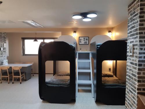 a room with three bunk beds and a table at La Masion Benie in Seogwipo