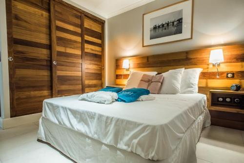 a bedroom with a large white bed with wooden walls at L'Appart du Tropiclub - bien-être à 2 pas du lagon in Filaos