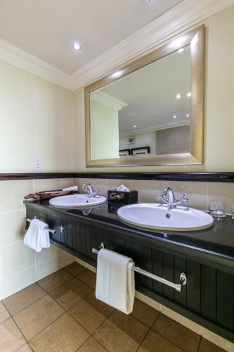 a bathroom with two sinks and a large mirror at Cresta President Hotel in Gaborone