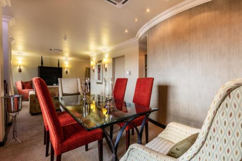 a dining room with a table and red chairs at Cresta President Hotel in Gaborone