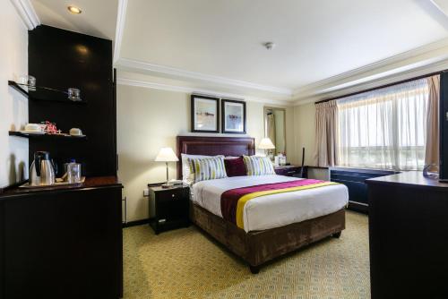 a hotel room with a large bed and a window at Cresta President Hotel in Gaborone