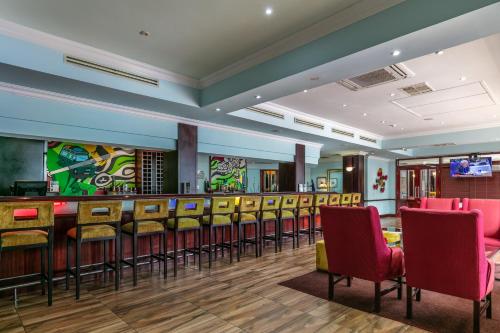 a bar in a restaurant with chairs and tables at Cresta President Hotel in Gaborone