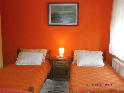 2 łóżka w pokoju z pomarańczową ścianą w obiekcie Apartman Katarina w mieście Beli Manastir