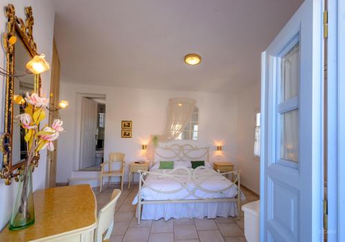 a room with a bed, table, chairs and a mirror at Chora Resort Hotel & Spa in Chora Folegandros