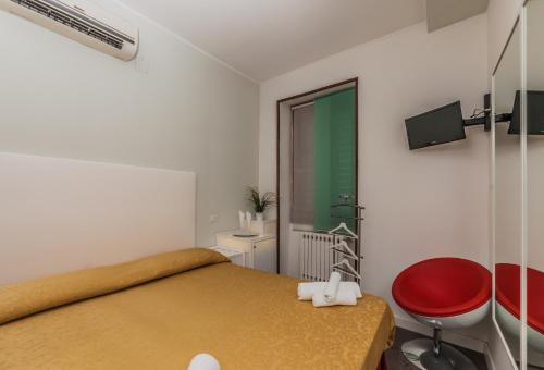 a small bedroom with a bed and a red chair at Albergo Della Corte in Benevento