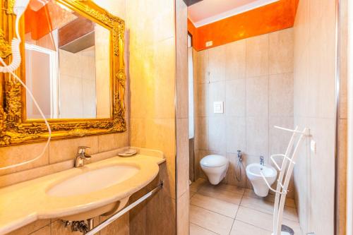 a bathroom with a sink and a toilet and a mirror at Albergo Della Corte in Benevento