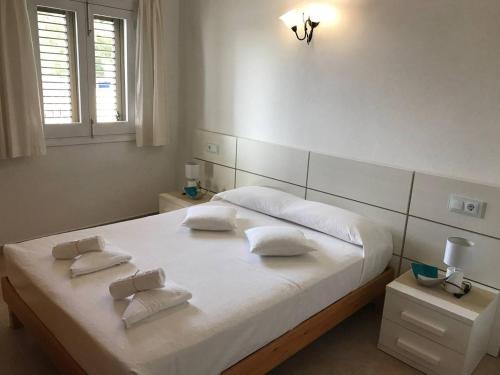 um quarto com uma grande cama branca e 2 almofadas em Casa S Estany em La Savina