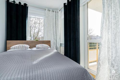 ein Schlafzimmer mit einem Bett und einem großen Fenster in der Unterkunft Jantar Apartamenty - Park Side in Kołobrzeg