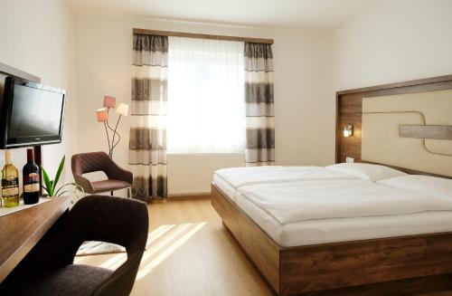 a bedroom with a bed and a desk and a television at NATIONALPARKHOF GARTNER Weingut-Gästehaus in Illmitz