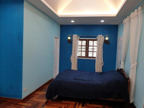 a blue bedroom with a bed and a window at Single House Sattahip in Sattahip