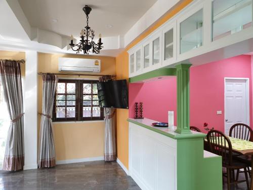 a kitchen with pink and yellow walls and a table at Single House Sattahip in Sattahip