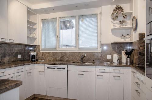 a white kitchen with white cabinets and a sink at House Lakeside – GriwaRent AG in Lungern