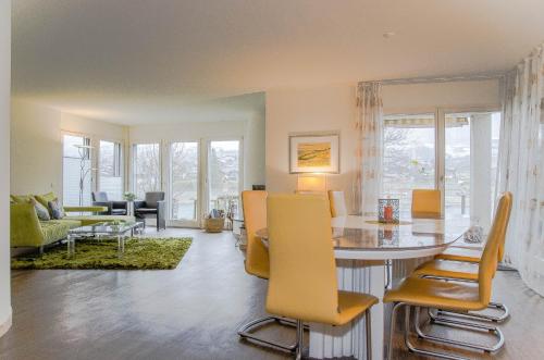 a dining room and living room with a table and chairs at House Lakeside – GriwaRent AG in Lungern