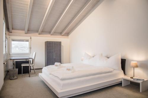 a white bedroom with a white bed and a piano at House Lakeside – GriwaRent AG in Lungern