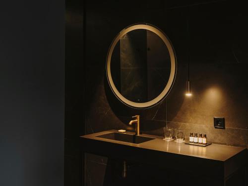 a bathroom with a sink and a round mirror at El Môderne Hotel in Gijón