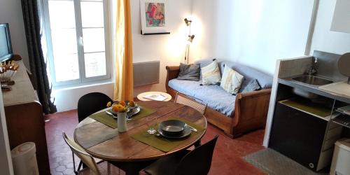 a living room with a table and a couch at Le nid des Arènes in Arles