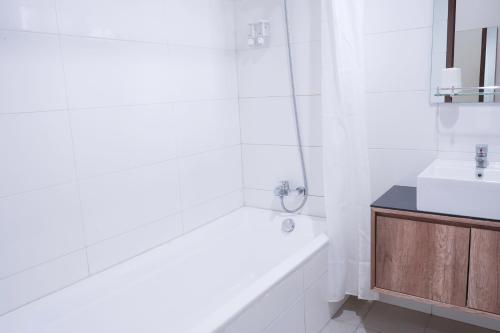 a white bathroom with a tub and a sink at Mk House Tendean in Jakarta