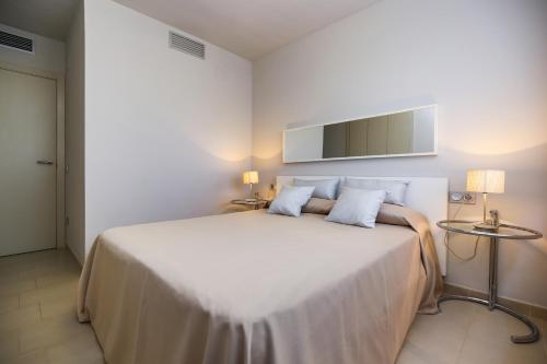 a bedroom with a large white bed with two lamps at Tropicana Planet Costa Dorada in Cambrils