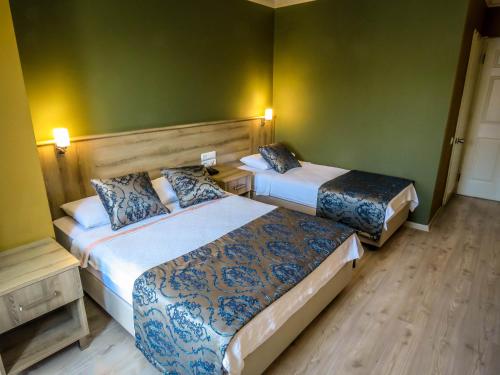 two beds in a hotel room with green walls at Remer Hotel in Fethiye