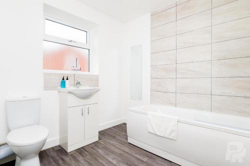 a white bathroom with a toilet and a sink at Birmingham Estate III By Prime Stays in Birmingham