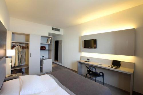 Schlafzimmer mit einem Bett und einem Schreibtisch mit einem TV in der Unterkunft Hotel Giardino in Arona