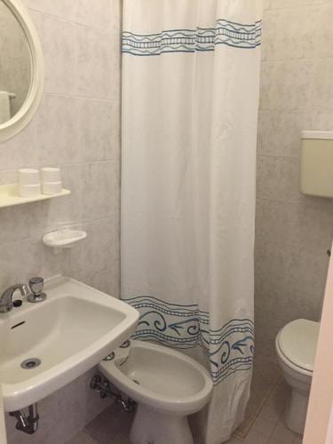 a bathroom with a sink and a toilet and a shower curtain at Hotel Ville De Paris in Riccione