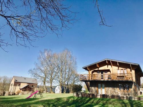 a wooden house with a deck on top of a field at Chalet de Charme in Rochehaut