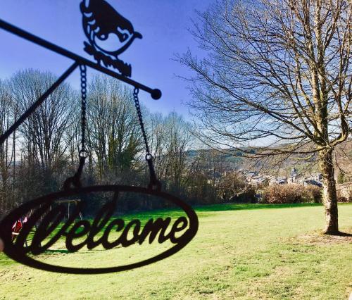 a swing in a field with a sign that says welcome at Chalet de Charme in Rochehaut