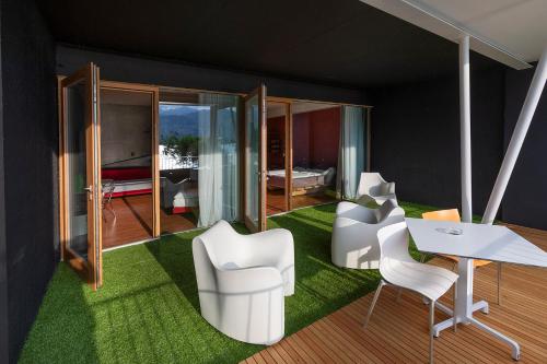 a room with white chairs and a table and a bedroom at Ambienthotel PrimaLuna 3S in Malcesine